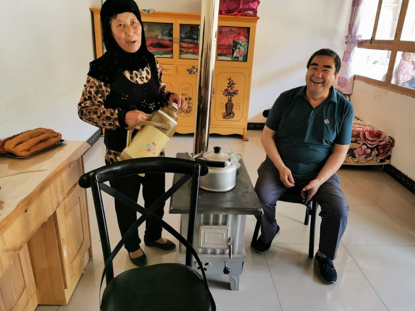 Madam Maa in her new home, preparing traditional Babao tea for one of the project staff members (right)
