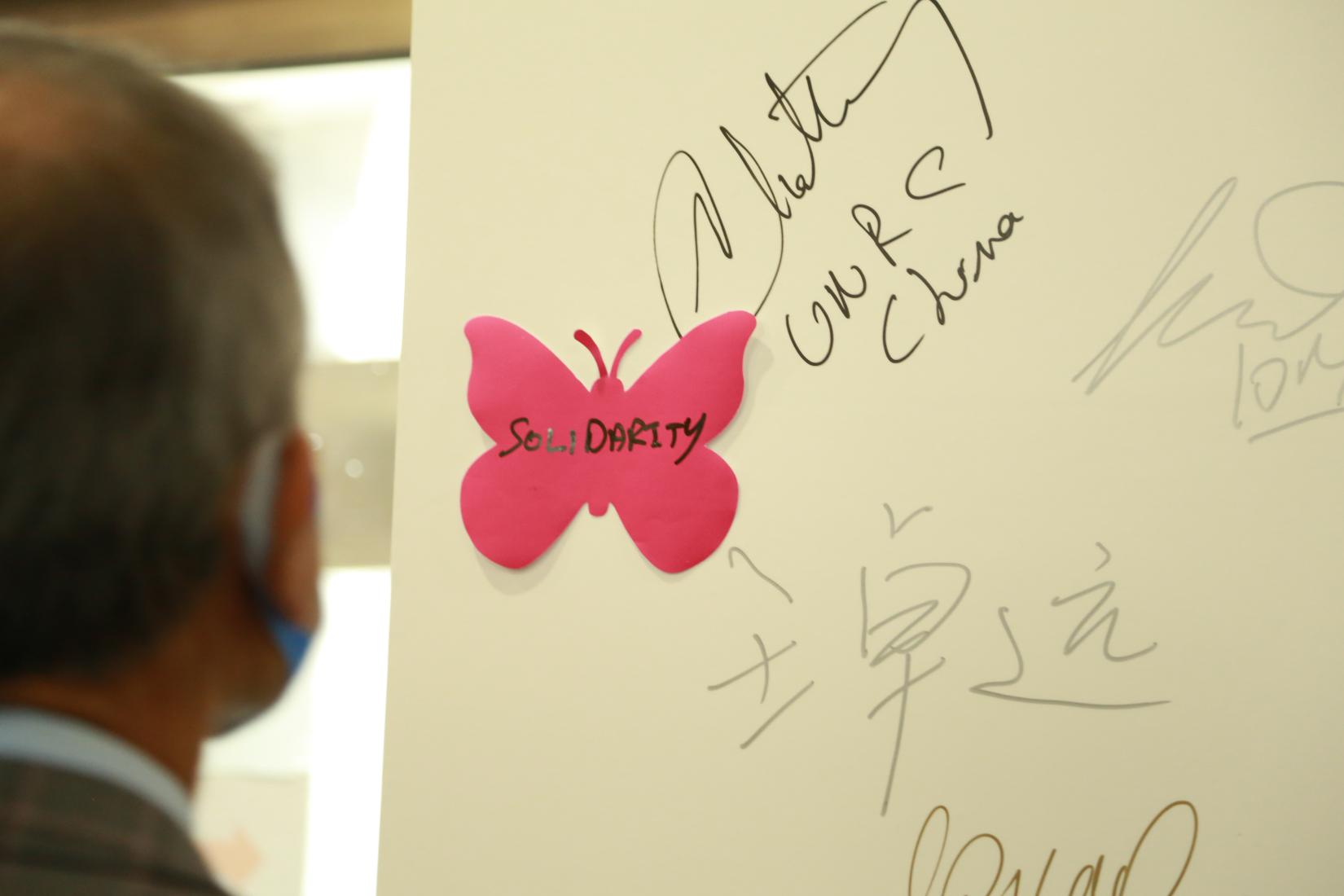 Participants sign wall at Zero Discrimination Day poster exhibition