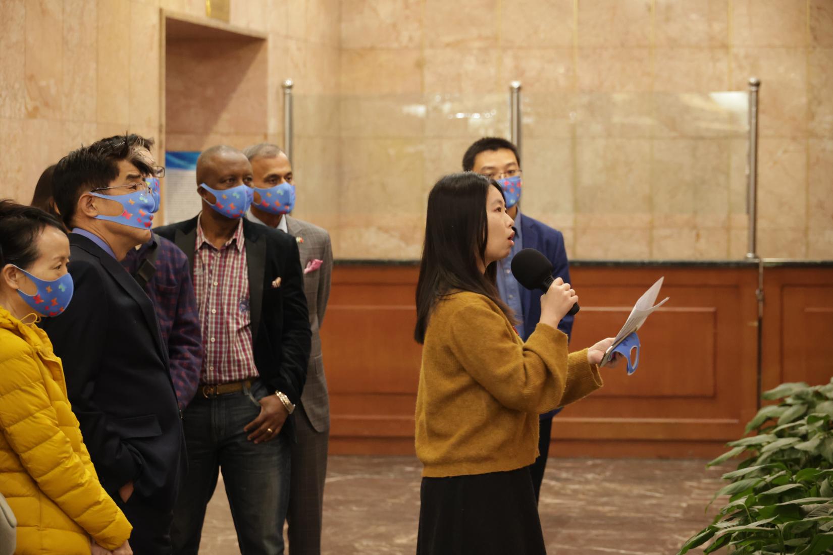 Weng Huiling (in front, holding a microphone) guides an exhibition tour on Zero Discrimination Day. ©UNV, 2022