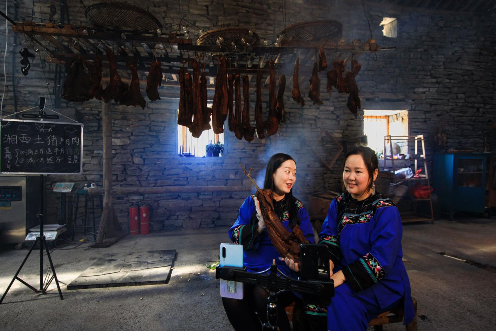 Jinyou (right) and a fellow villager livestream in rural Fenghuang County, China.