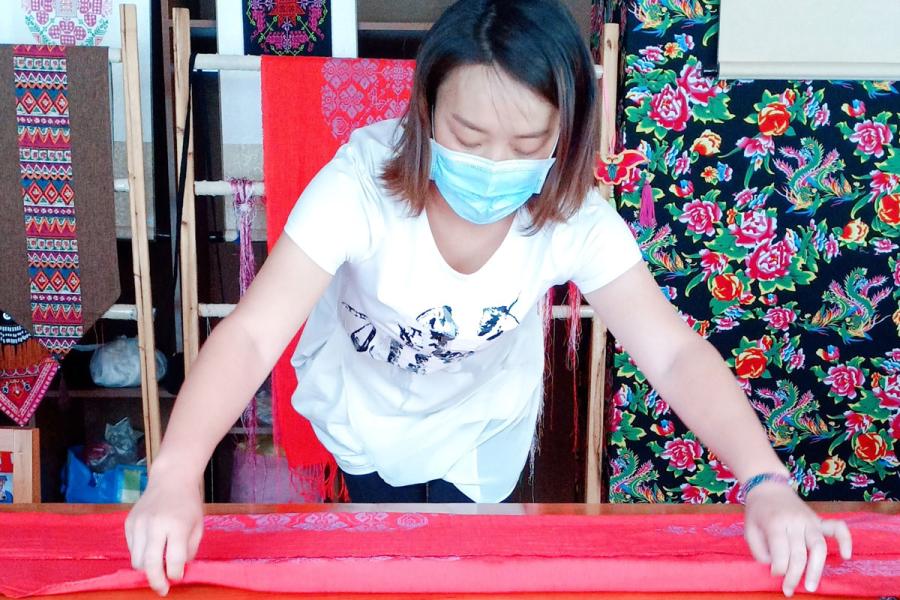 A member of the Women Embroidery Farmers Cooperative, working at the cooperative centre, shares her progress over WeChat.