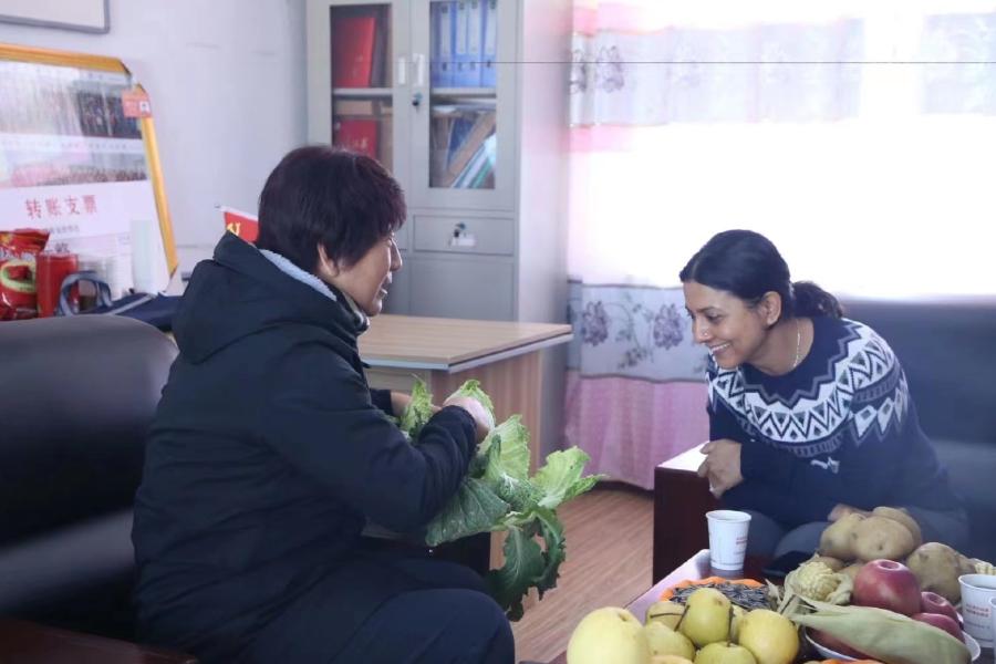安思齐女士考察联合国妇女署青海项目试点村，与驻村第一书记聊天。驻村第一书记正在介绍当地妇女主导的农业合作社的农产品。